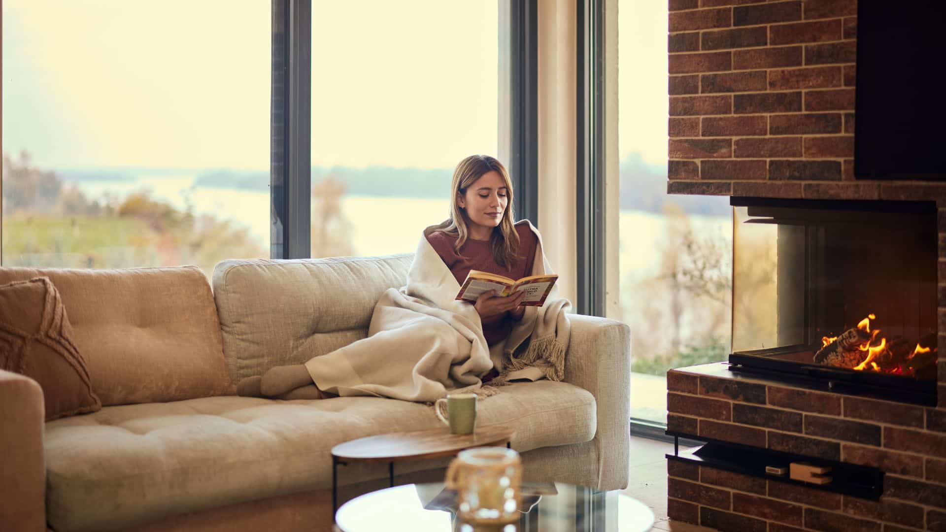 Woman relaxing indoors by a fireplace, reflecting the calming northern lights strain effects