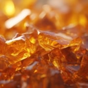 Close-up of amber, glass-like cannabis concentrate pieces, showing the brittle texture typical of shatter THC.