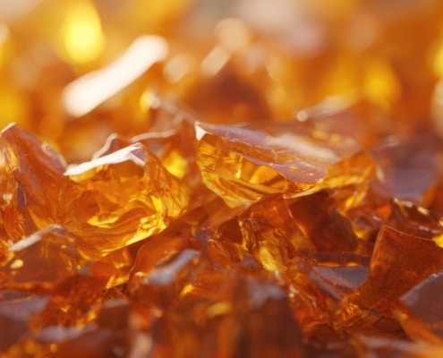 Close-up of amber, glass-like cannabis concentrate pieces, showing the brittle texture typical of shatter THC.
