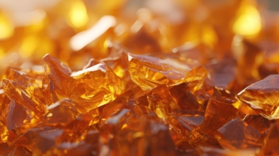 Close-up of amber, glass-like cannabis concentrate pieces, showing the brittle texture typical of shatter THC.